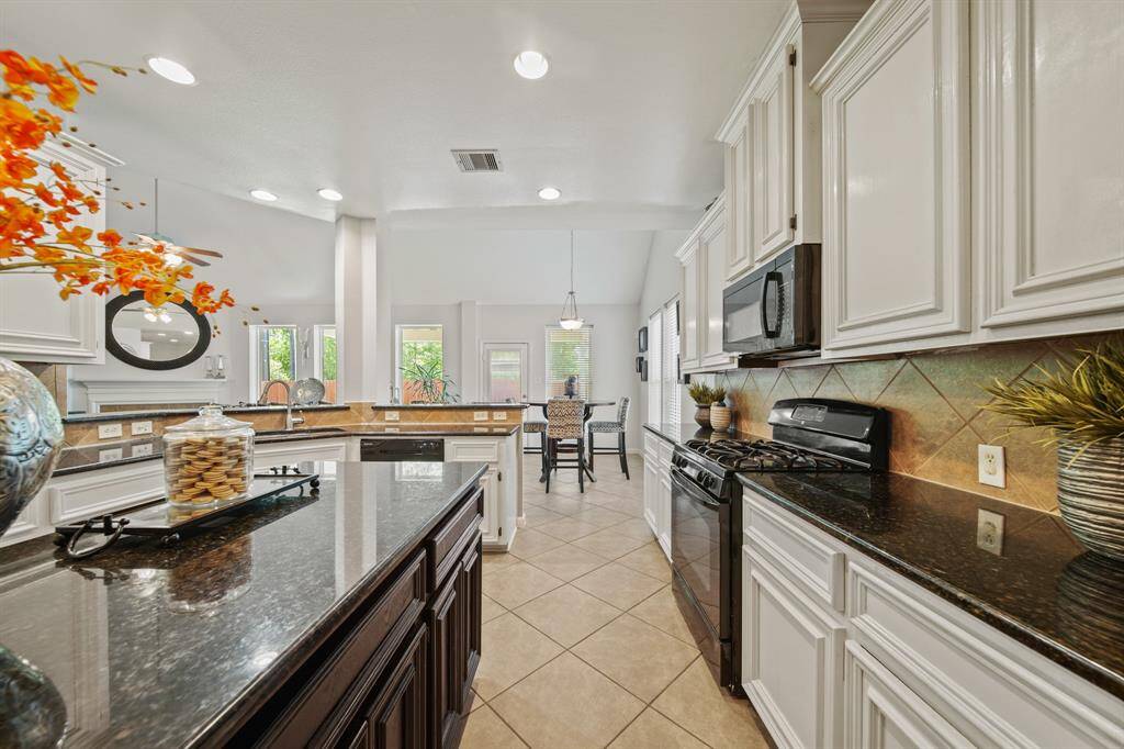 The kitchen flows effortlessly into the breakfast nook and family room, offering a connected, airy feel with views of the backyard and beyond.