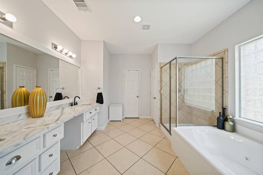 The ensuite bathroom boasts a long double-sink vanity with marble-look counters and plenty of storage to keep everything organized.