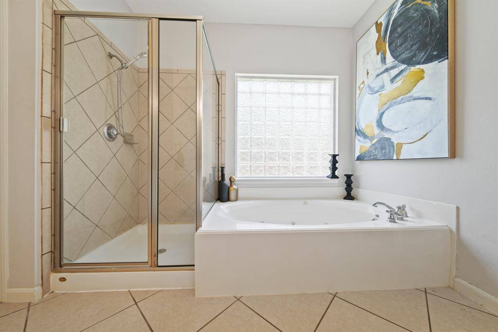 Enjoy the luxury of a spa-inspired jetted tub and separate glass-enclosed shower, all bathed in soft natural light from a glass block window.
