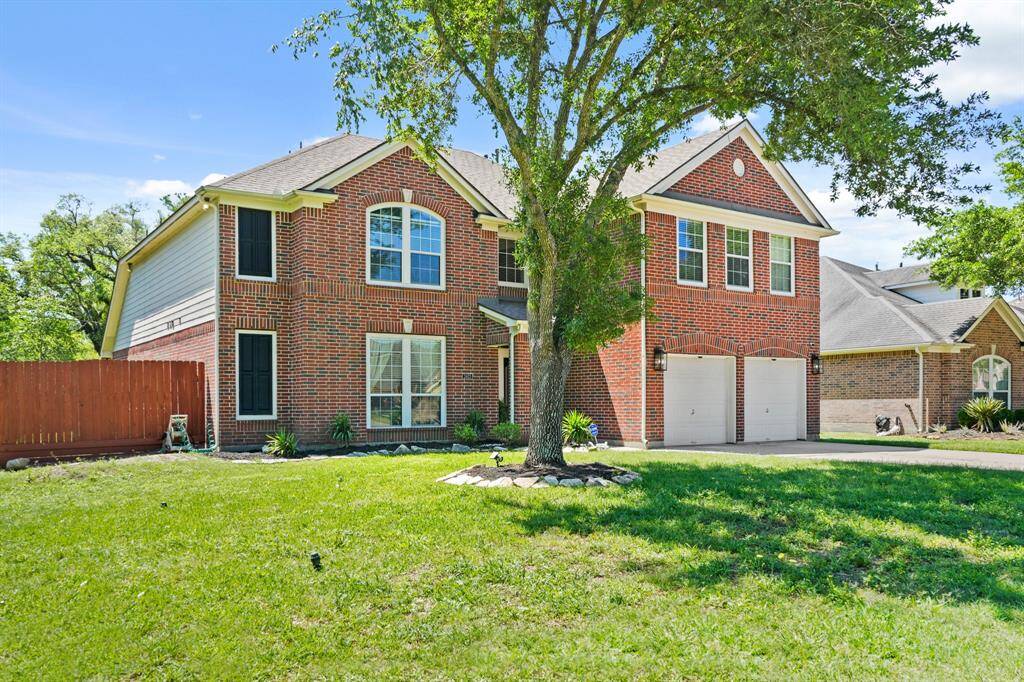Enjoy ample parking with a long double-wide driveway leading to the attached 2-car garage, surrounded by lush greenery.