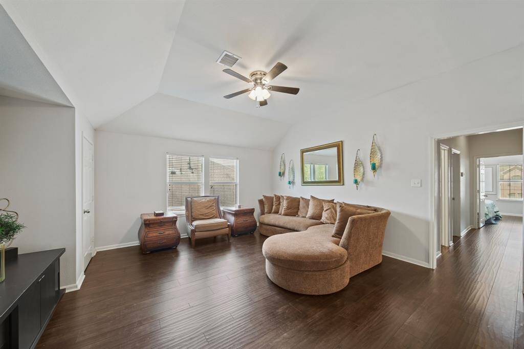 Natural light floods the game room through dual windows, highlighting the beautiful wood flooring and open layout that connects easily to the upstairs bedrooms.