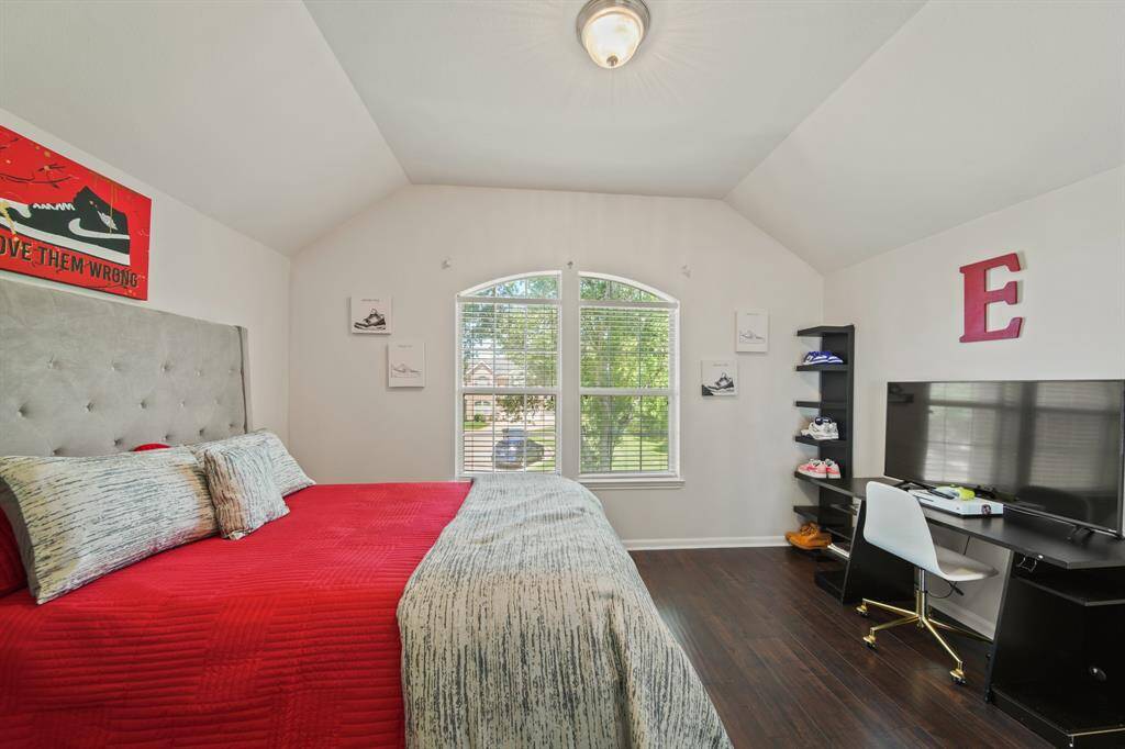 Vaulted ceilings and a large arched window fill this guest retreat with natural light, offering a serene space with warm wood-style flooring and fresh neutral finishes.