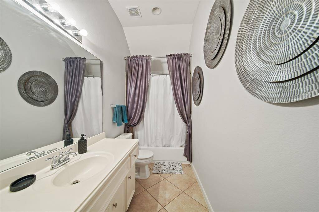 Serving both additional guest bedrooms, this well-appointed bathroom includes a full tub/shower combo, extended vanity, framed mirror, and neutral tile flooring.