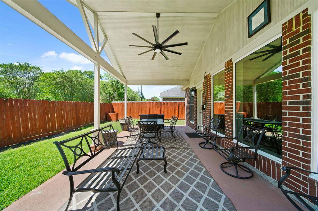 Enjoy your mornings or unwind in the evening beneath the expansive covered patio featuring a soaring ceiling and ceiling fan for added comfort.