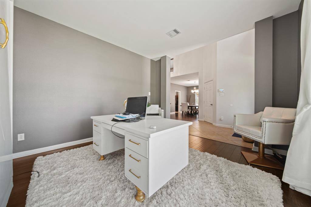 Located just off the foyer, this spacious home office features rich wood flooring, soothing neutral tones, and a wide front-facing window that fills the room with natural light.