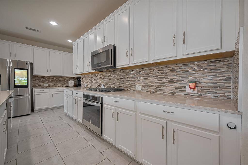Closer Detail of the mosaic tile backsplash, built in Stainless steel Appliances and Smart Fridge that will stay with the property.