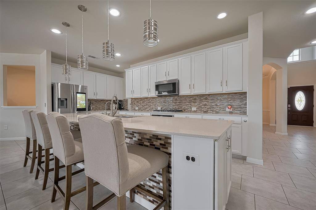 Sleek and modern with timeless appeal, this kitchen includes pendant lighting, recessed ceiling lights, and a smart fridge that adds a tech-savvy touch to this well-appointed space.