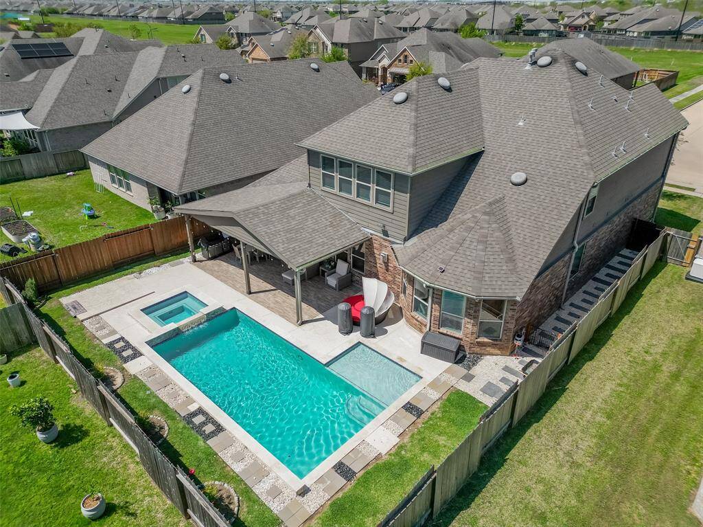 Stunning aerial view showcasing your private backyard oasis, complete with a sparkling pool, raised spa, and expansive covered patio — ideal for summer gatherings and relaxation.