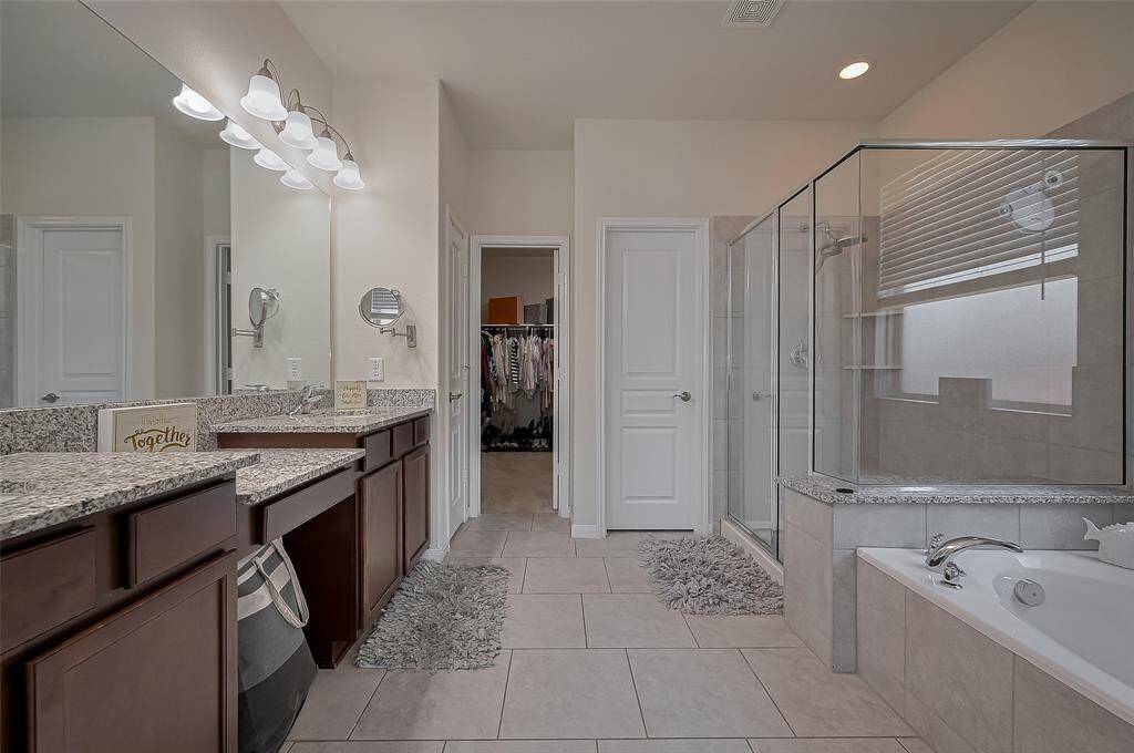 Unwind in the oversized soaking tub nestled beneath a frosted privacy window. Beautiful tilework and a relaxing atmosphere make this space a serene escape