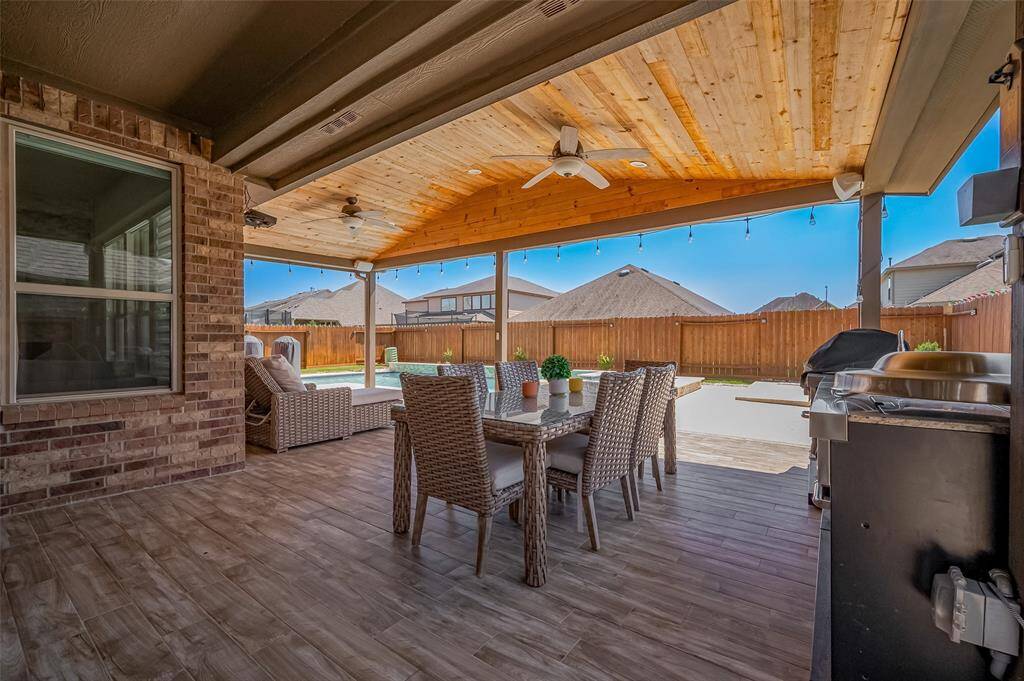 Unwind or entertain under this stunning vaulted covered patio, complete with tongue-and-groove wood ceilings, dual ceiling fans, and recessed lighting. The elegant tile flooring resembles rich hardwood, creating a warm and inviting space perfect for dining and relaxing year-round.