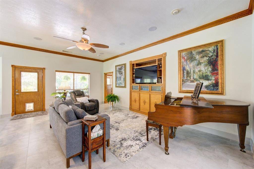 Living room with large ceiling fan and floor plug.  Custom 6" baseboards