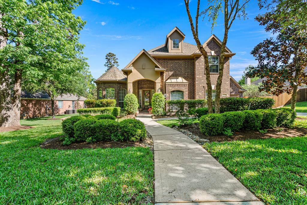 This Beautiful Brick Home features 4-5 Bedroom with a 3 Car Garage, well-manicured yard with lush greenery and a curved walkway leading to an inviting entrance.