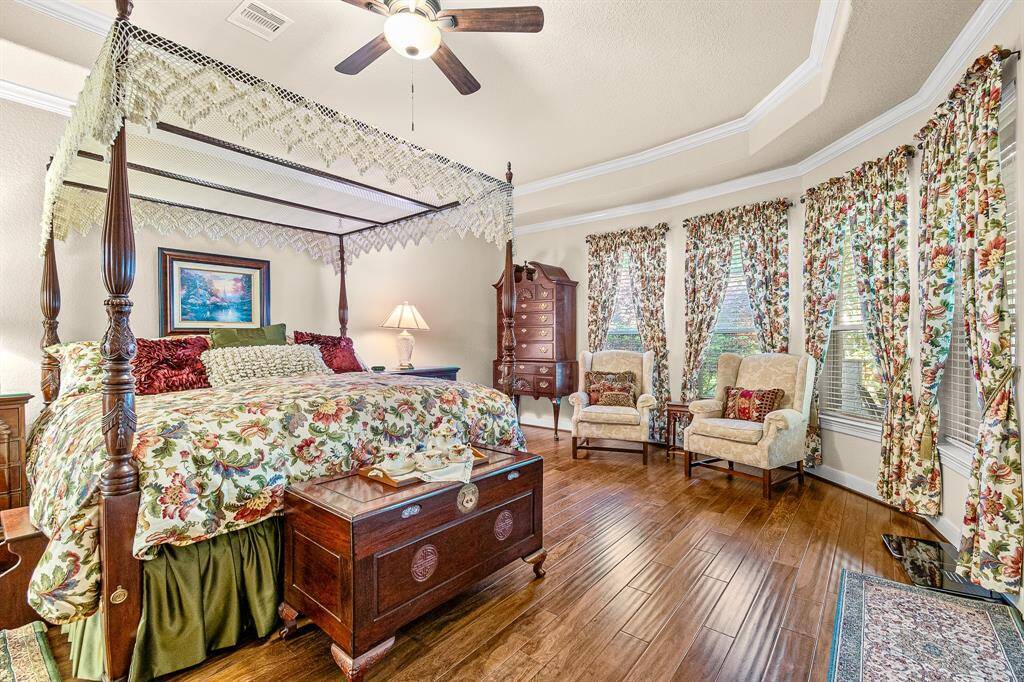 Your Primary Suite provides an elegant bedroom that features 4 Large windows that allows natural light, trayed ceilings with double crown molding, while comfortable seating and classic furniture add charm.