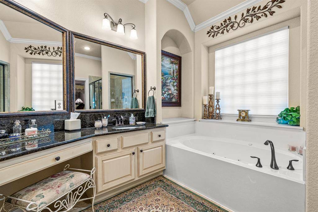 The Primary en-Suite bathroom features a luxurious Jetted soaking tub, granite countertops, dual vanities and vanity area. Elegant fixtures and decorative accents create a sophisticated atmosphere.
