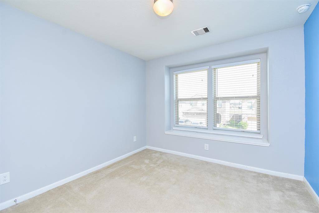 The second bedroom offers a cozy and welcoming space with soft carpet underfoot and soothing neutral tones. A large window lets in plenty of natural light, creating a cheerful atmosphere.