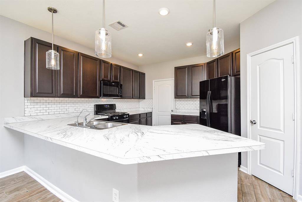 The kitchen is designed for both beauty and function, with sleek modern pendant lights that add a touch of charm.