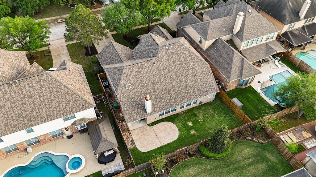 This oversized lot features both front and back green space, creating a buffer of privacy and space between neighbors. The 3-year-old roof and newer AC unit are visible from above—testament to the homeowner's proactive maintenance and investment in the property.