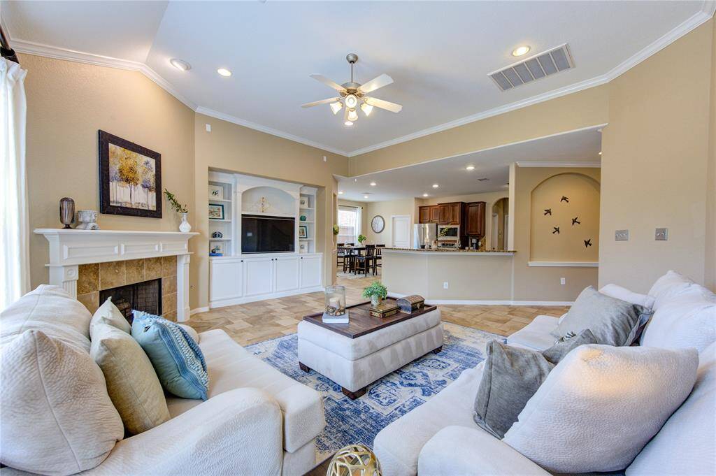 The heart of the home is the spacious and inviting living room, featuring high ceilings, expansive windows overlooking the backyard, and a cozy gas fireplace framed by tile surround. A perfect setting for relaxing with family or entertaining guests.
