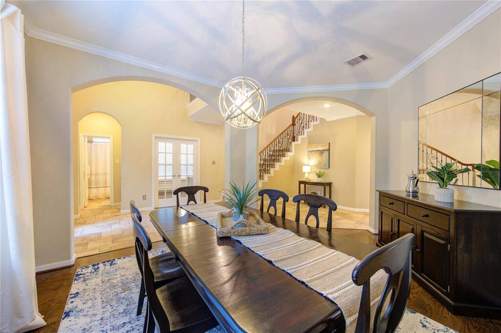 The elegant formal dining room features rich wood flooring, classic crown molding, and a modern chandelier that adds a touch of contemporary flair. The space is perfectly sized for hosting dinner parties or holiday gatherings, with architectural details that enhance the room’s warmth and sophistication.