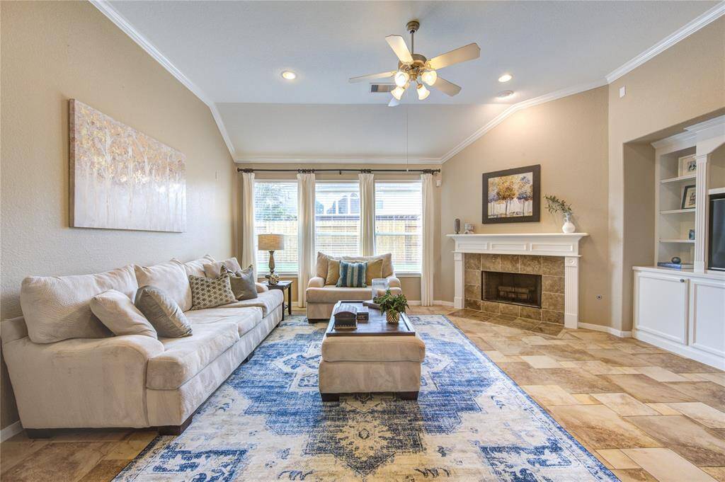 Bright and spacious, the living room features an open floorplan with soaring ceilings and abundant natural light. A wall of double-pane picture windows frames peaceful views of the backyard while enhancing energy efficiency.
