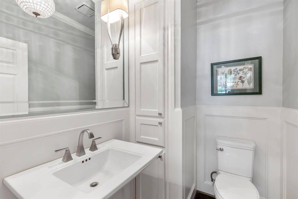 Elegant powder bath featuring classic wainscoting and a stunning chandelier that adds a touch of glamour.