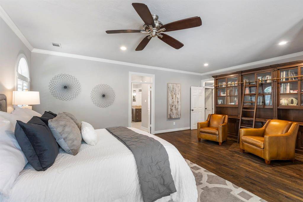 Custom built-in shelving and a cozy sitting area create a warm, spacious feel in this inviting primary retreat.
