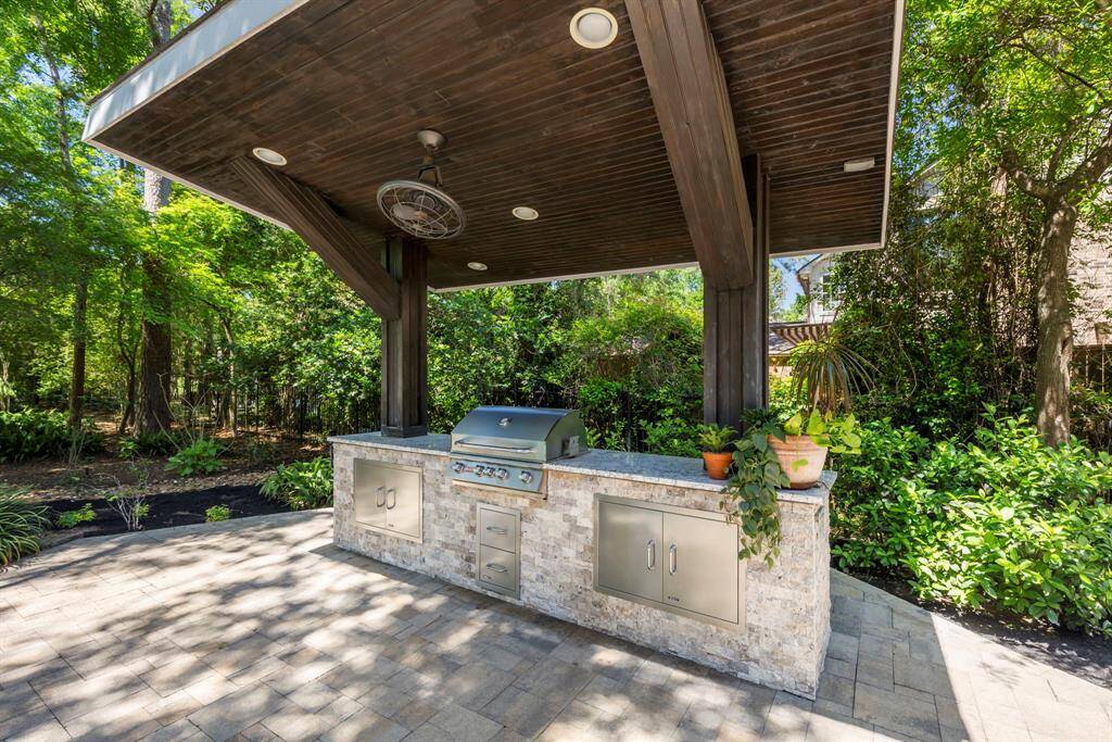 Enjoy cooking in the covered outdoor kitchen, featuring a grill, and ample storage with cabinets and drawers for convenient alfresco dining.