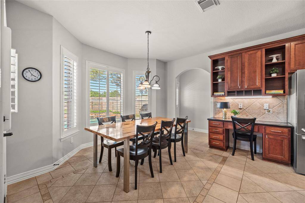 The breakfast room is ideal for a full-sized table and features easy care tile floors, large bright windows, overhead chandelier, and an additional desk area with coordinating counter and cabinet space.