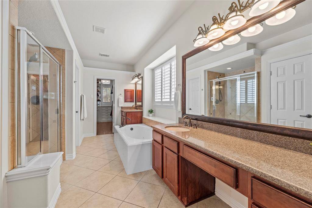 The primary bath features exquisite dual vanities, providing ample personal space along with an abundance of custom cabinetry for seamless organization.