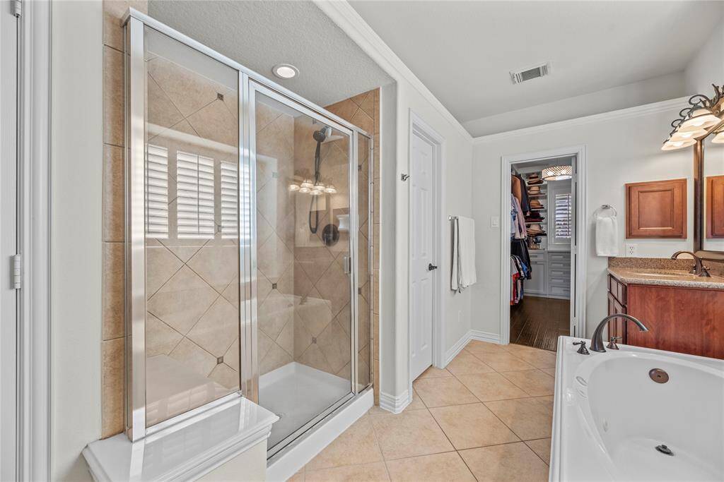 The expansive walk-in shower, adorned with stunning tile work and a sleek glass front, offers a luxurious escape for a quick rinse or a refreshing retreat.