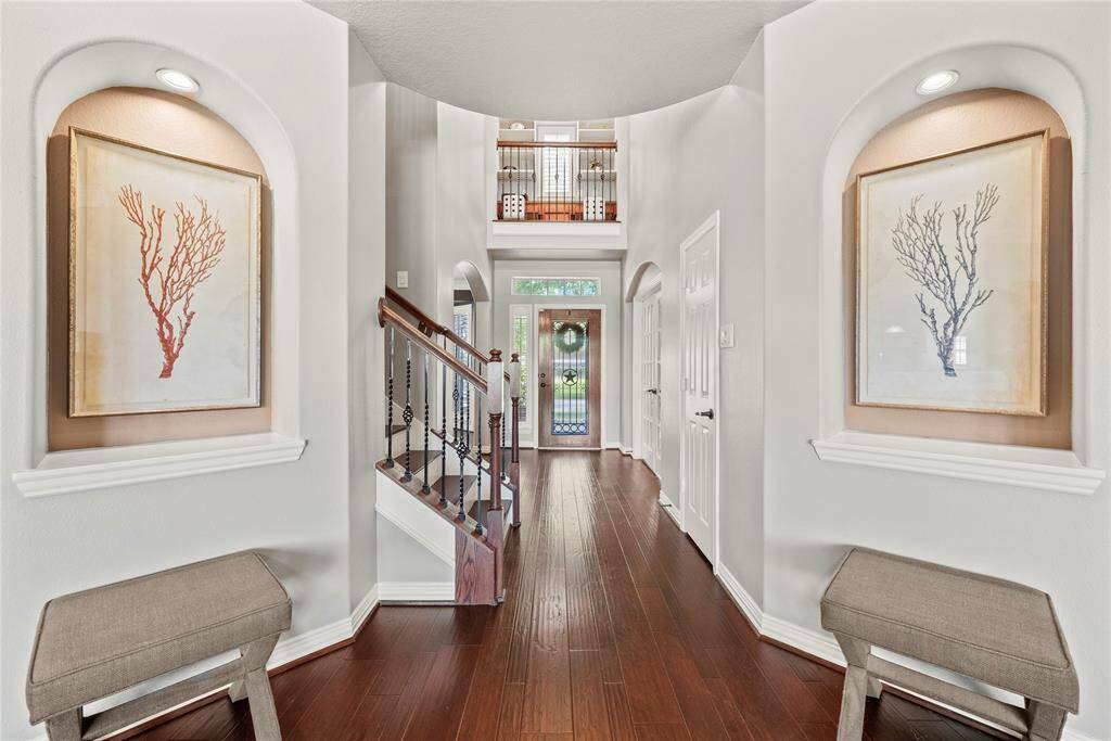 The stunning entryway welcomes you with rich engineered wood flooring, an abundance of natural light, and a warm, inviting ambiance.