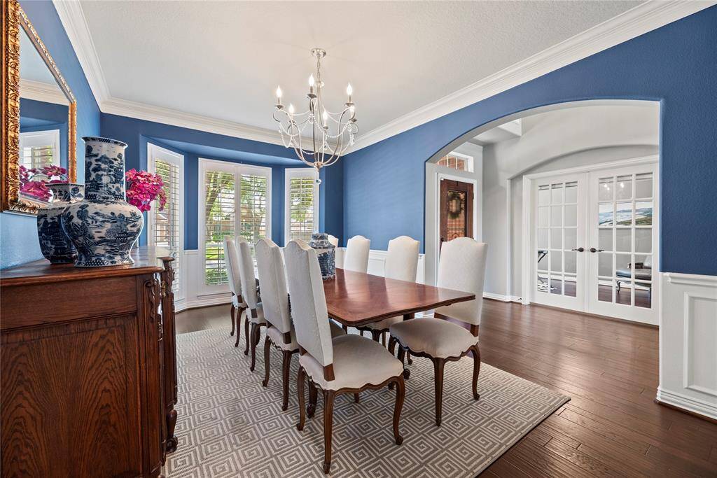 Elegant crown molding, a statement chandelier, engineered wood flooring, and custom shutters add timeless charm and sophistication to the space.