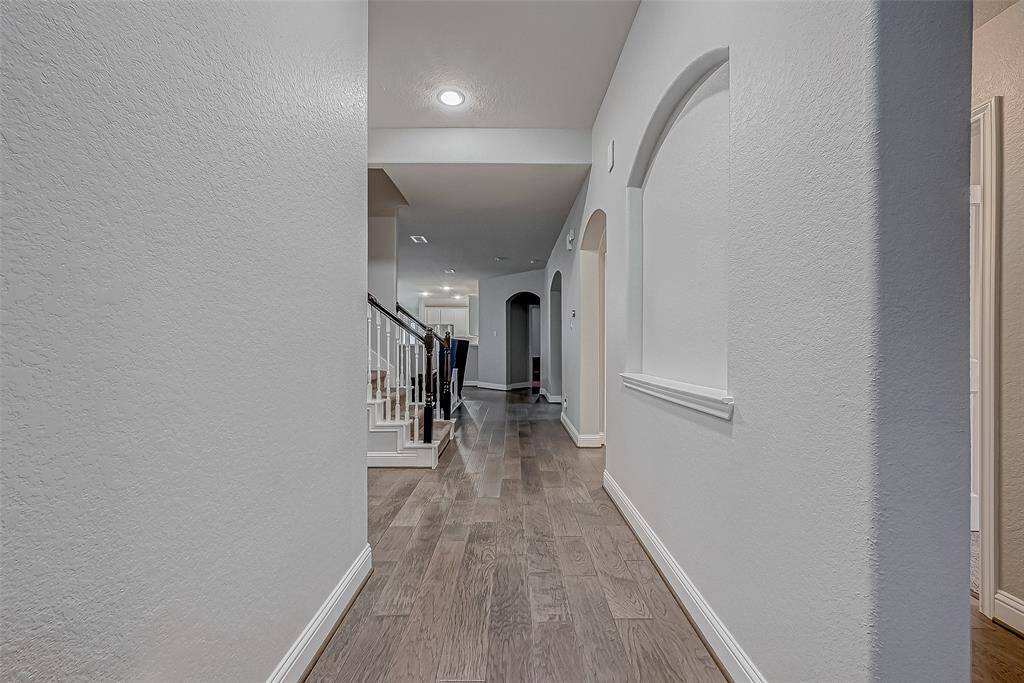 A row of charming archways along the right side adds character and depth to this entryway. The layout provides a subtle glimpse of the stairs and hints at the spaciousness beyond.