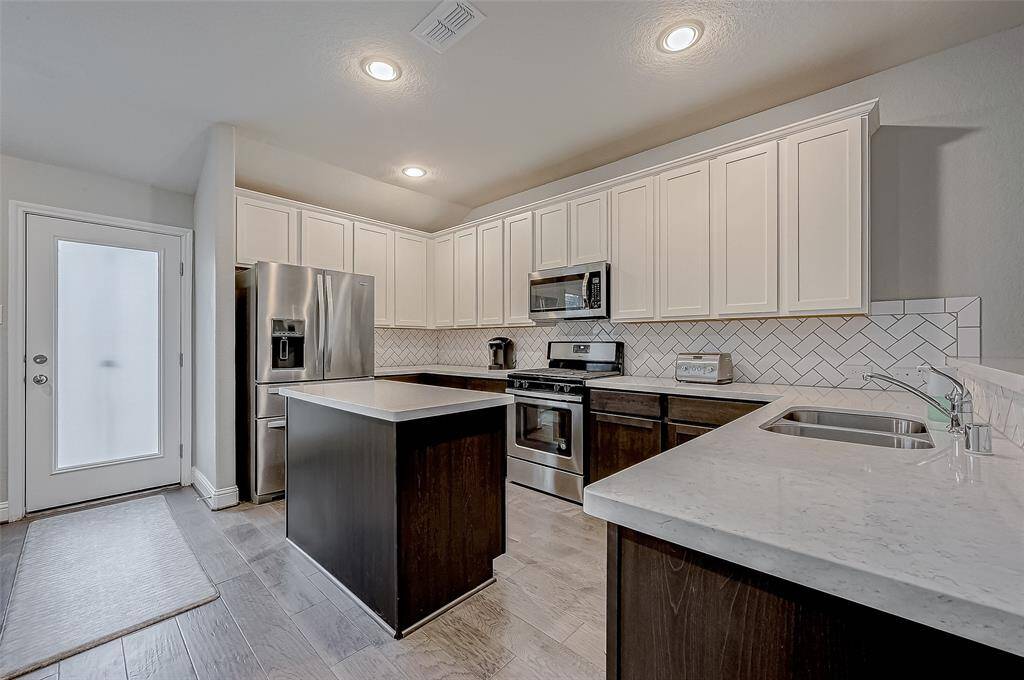 The kitchen features a convenient layout, complete with stainless steel appliances, spacious countertops, and abundant cabinet storage. The central island adds extra workspace and seating potential.