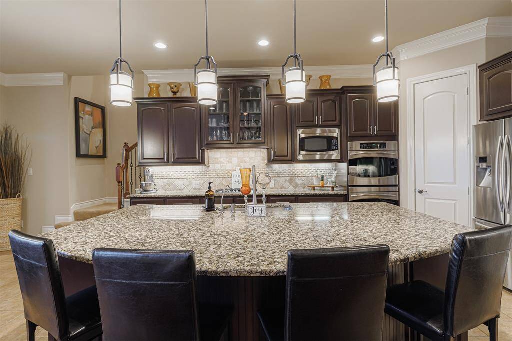 The island kitchen features granite counters, breakfast bar, recessed and pendant lighting. Along with 2 food pantries.