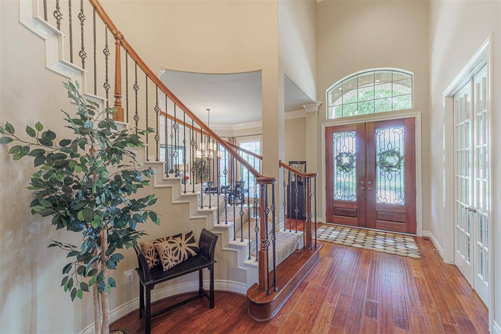 The 2-story entry features double doors, wood flooring and wrought iron staircase.