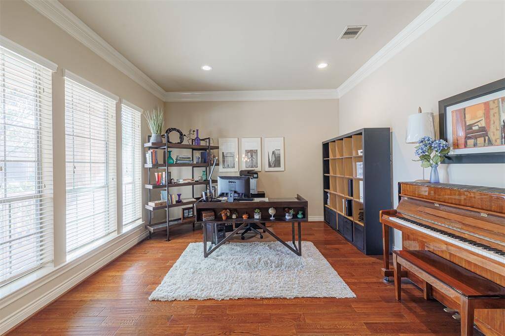 A private study with French doors, crown molding and wood flooring located off the front entry.