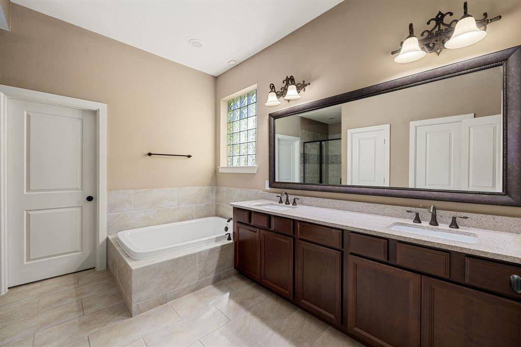 This primary bathroom is definitely move-in ready! Featuring a framed oversized walk-in shower with tile surround, separate garden tub for soaking after a long day with custom tile detailing, dark stained cabinets with granite countertops, spacious walk-in closet with shelving, high ceilings, custom paint, sleek and modern finishes.