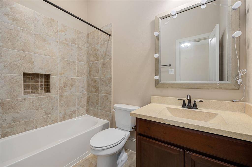 Secondary bathroom features light countertops and cabinets, neutral paint, shower/tub combo with tile surround, large mirror, tile floors, sleek fixtures and modern finishes, plenty of space to accommodate any visiting family or guests.