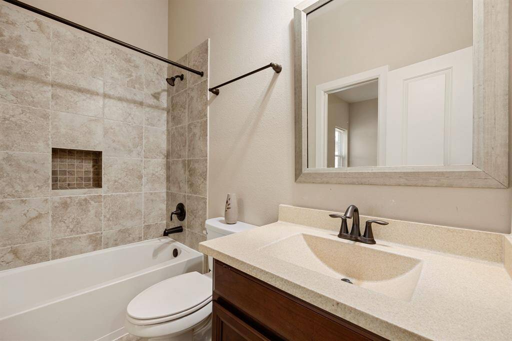 Secondary bathroom features light countertops and cabinets, neutral paint, shower/tub combo with tile surround, large mirror, tile floors, sleek fixtures and modern finishes, plenty of space to accommodate any visiting family or guests.