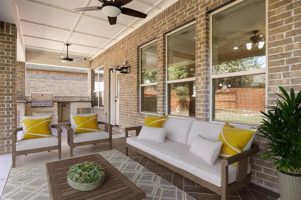 This inviting covered patio offers a perfect outdoor retreat with beautiful brick walls and large windows that provide a view into the home’s interior. The space includes dual ceiling fans for comfort and an impressive built-in grill, ideal for outdoor cooking and entertaining. With ample room and a stylish, laid-back vibe, this patio is ready to become the heart of outdoor gatherings or a peaceful spot to unwind.
