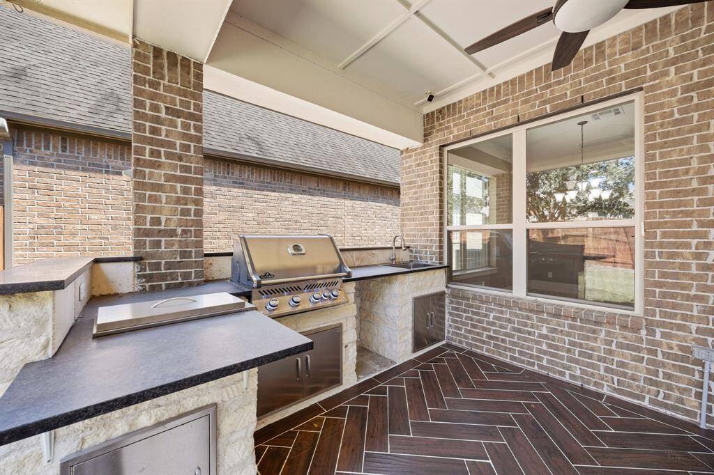 This outdoor kitchen is a chef's dream, featuring a built-in grill, ample counter space, and durable finishes designed to withstand the elements. Perfect for entertaining, it offers everything needed to host gatherings, from casual BBQs to elegant outdoor dinners.