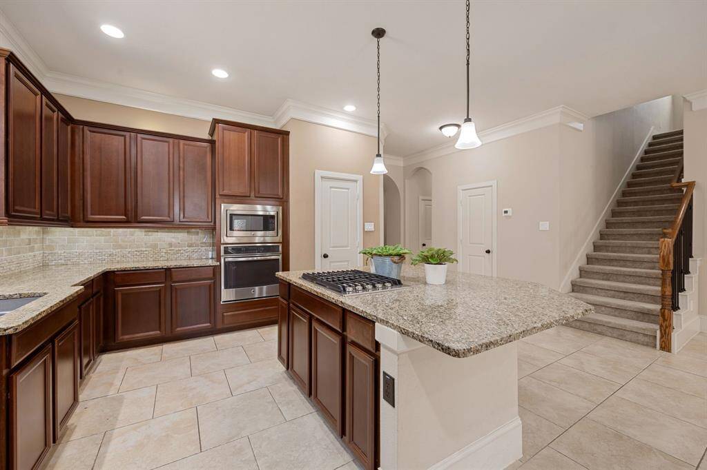 This kitchen is by far any chef’s dream! This spacious kitchen features high ceilings, dark stained wood cabinets, granite countertops, SS appliances, modern tile backsplash, recessed lighting with additional custom pendant lighting, extended counter space, granite kitchen island with space for breakfast bar and a spacious pantry all overlooking your huge family room.