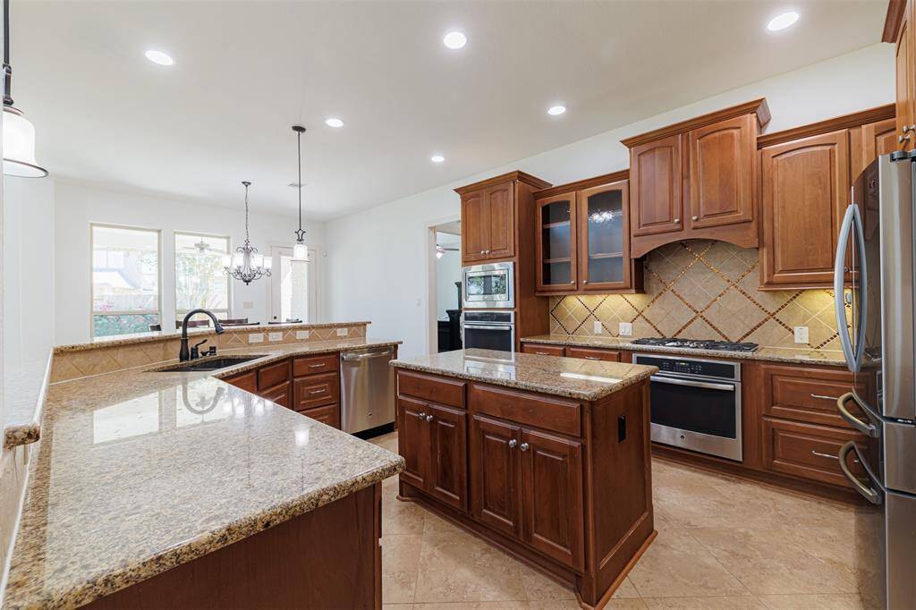 The island kitchen features granite counters, tile flooring, recessed and pendant lighting.