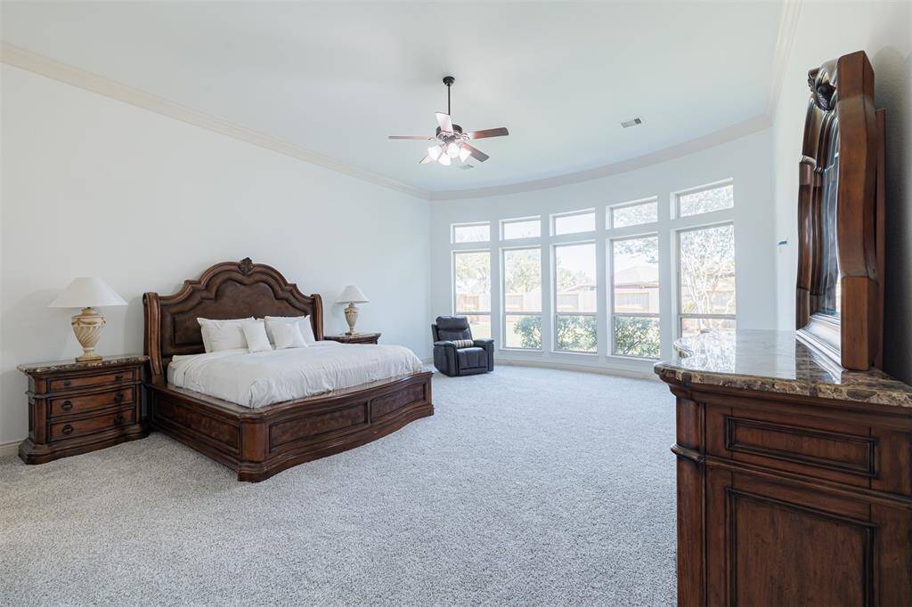 Large primary suite with high ceilings and a wall of windows overlooking the backyard.