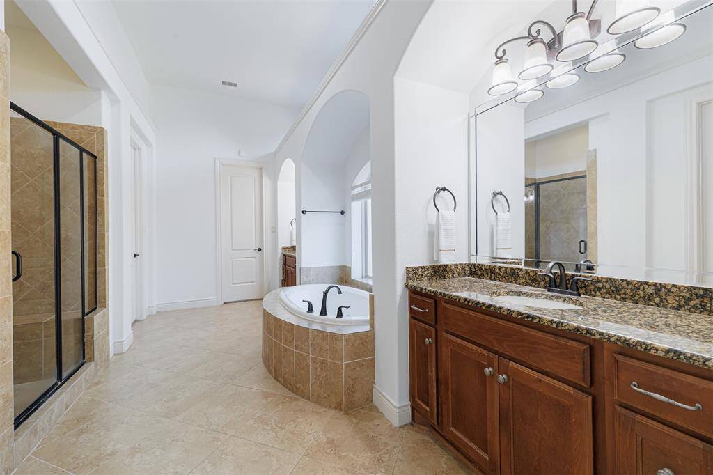 Spa-like primary bath with dual sink areas and tile flooring.