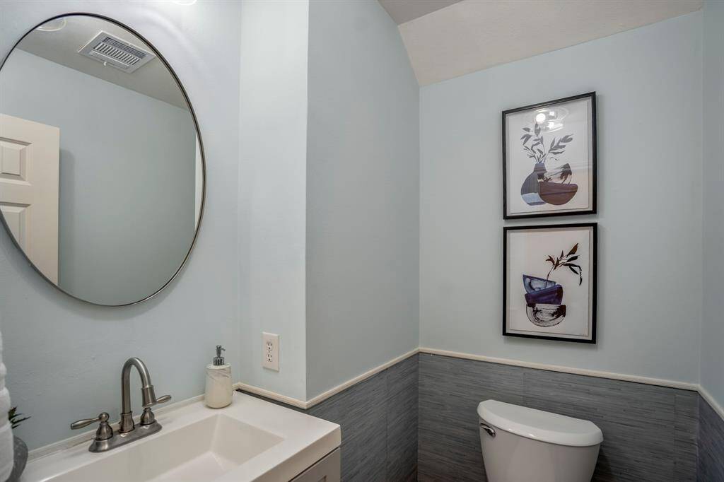 This bathroom features a modern design with light blue walls, a stylish oval mirror, and a sleek sink with a chrome faucet complementing the calming atmosphere.