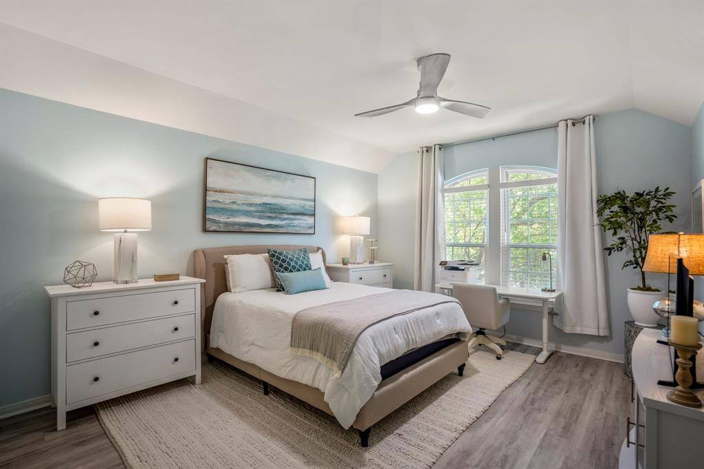 The primary bedroom offers beautiful arched windows and modern ceiling fan.