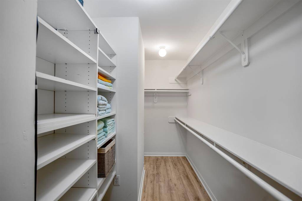 Spacious walk-in closet with ample shelving and hanging space, featuring a bright, well-lit interior and wood-style flooring.