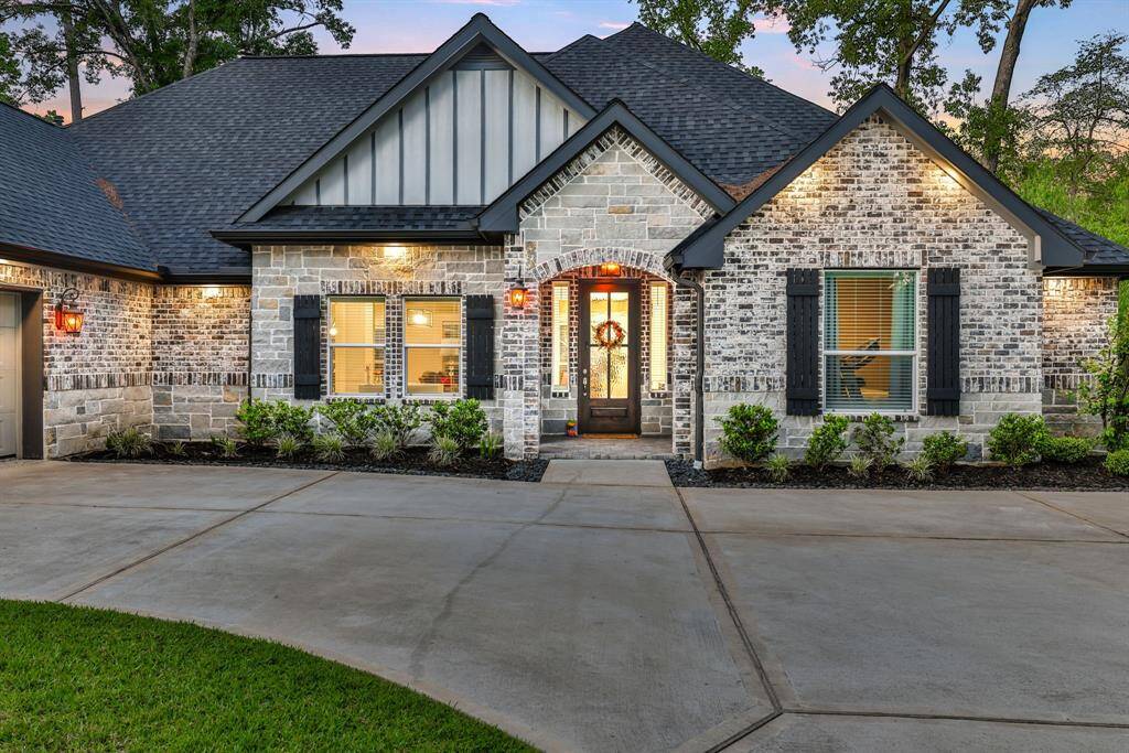 Discover this charming single-story brick home, featuring a spacious driveway, two-car garage, and pristine landscaping. The gabled roof, modern lighting, and inviting entrance are nestled among mature trees, creating a perfect retreat.